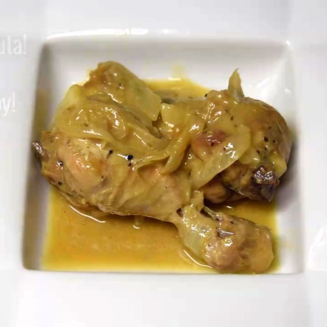 Pollo guisado con cerveza y cebollas servido en un plato listo para disfrutar.